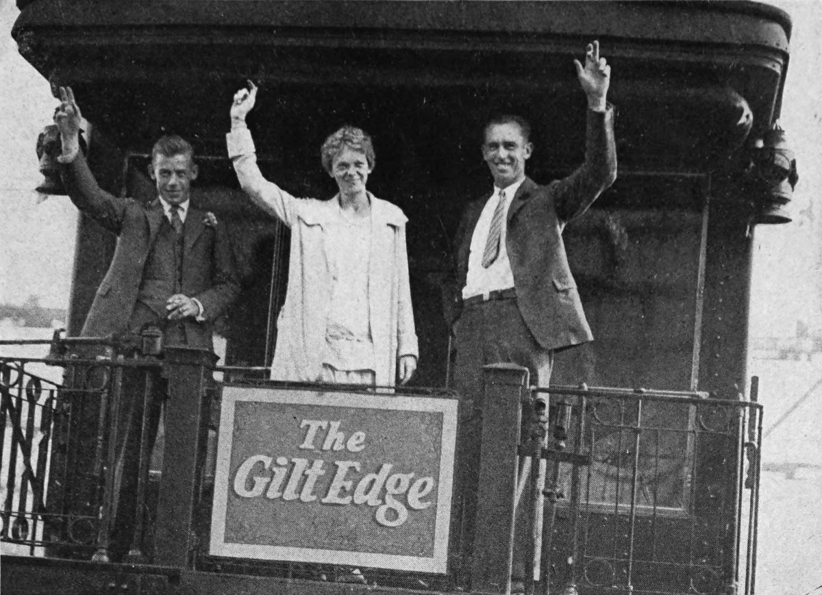 Photo wide outdoor shot of Friendship waving from rear platform rail car; a sign saying “The Gilt Edge”
                hangs on railing